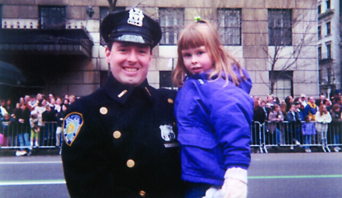 A police officer holds a young girl in a purple coat