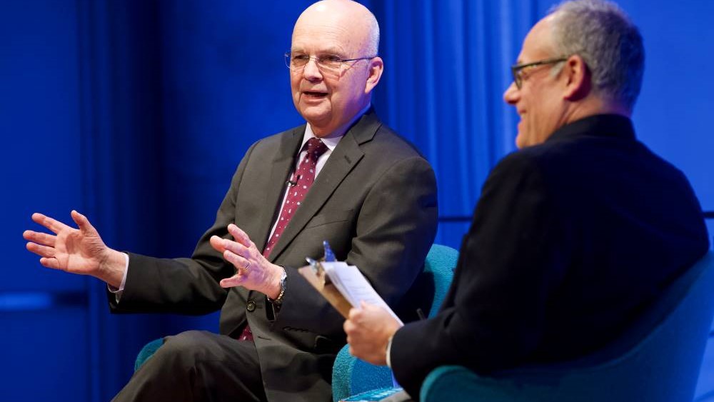 Former CIA director and retired U.S. Air Force Gen. Michael Hayden gestures with both hands onstage as part of the public program, General Michael Hayden on the War on Terror. He is seated next to Clifford Chanin, the executive vice president and deputy director for museum programs, who is smiling as he looks out at the audience.