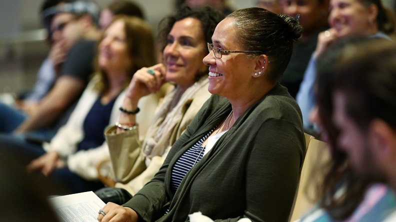 Teachers sit smiling in a professional development conference in the Museum auditorium.