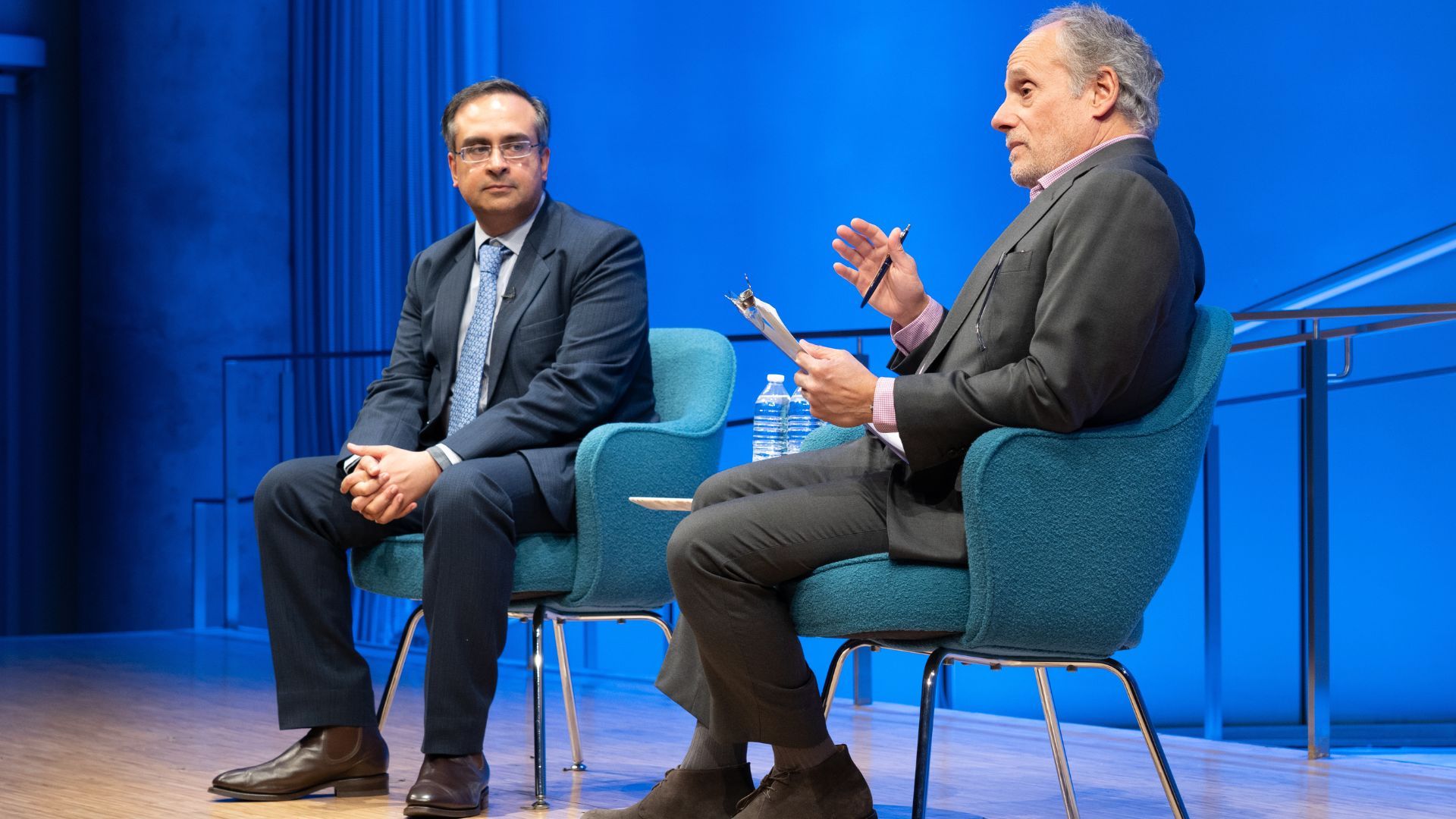 From left: Dr. Sajjan Gohel and Clifford Chanin (speaking) on stage.