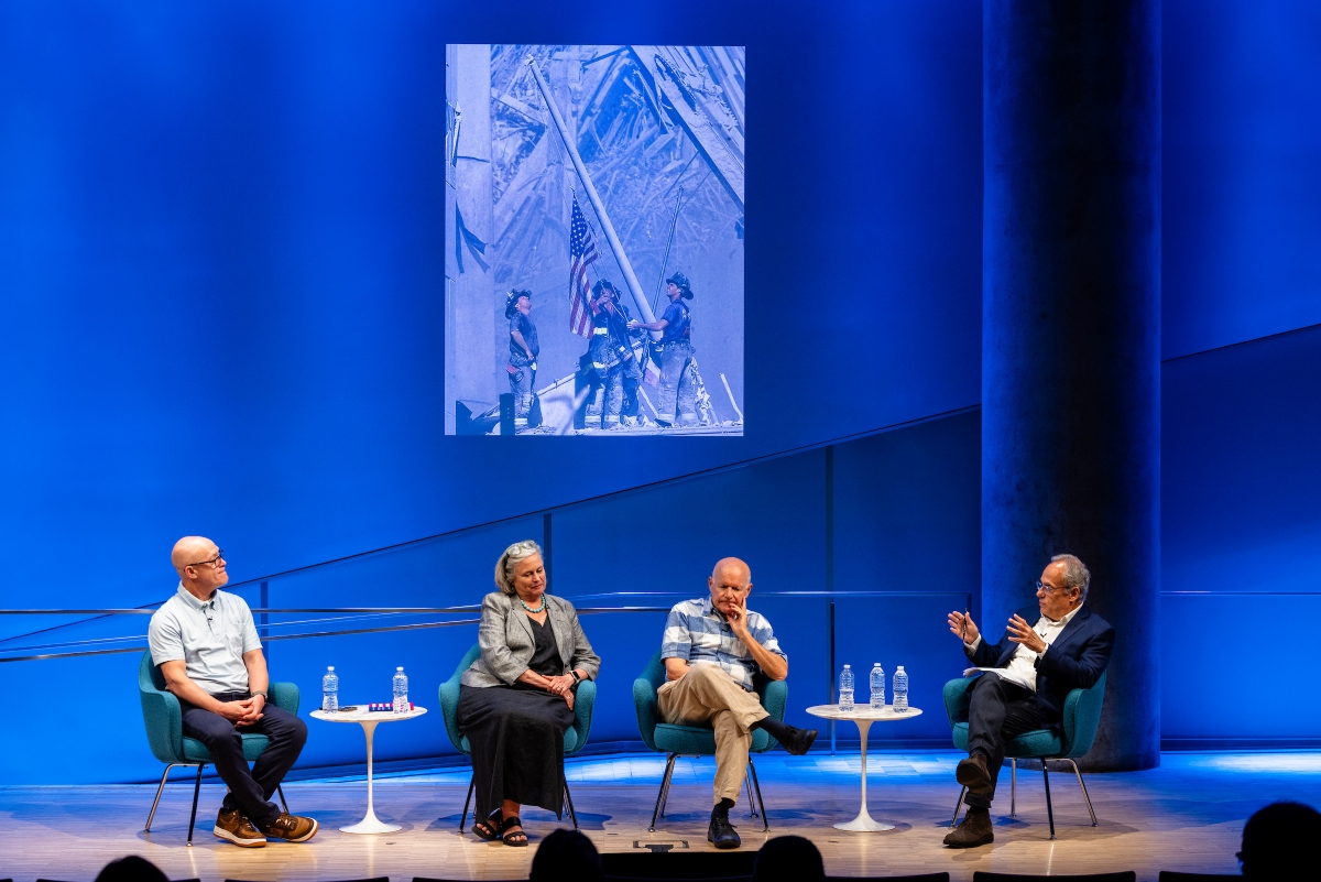 four people on stage under a large image of Ground Zero
