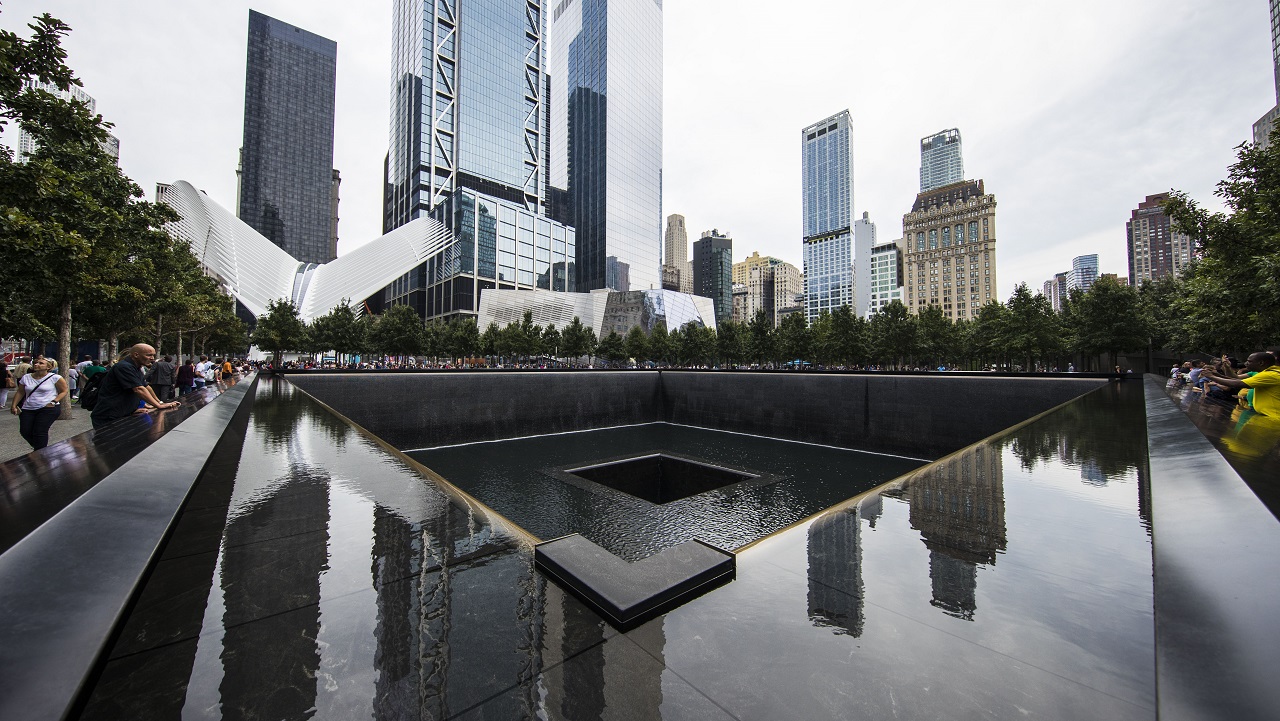 The surrounding buildings of the World Trade Center site are seen reflected in the memorial pool on an overcast day.
