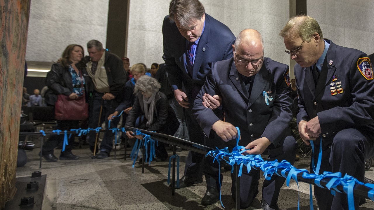 Three men tie blue ribbons in the Museum