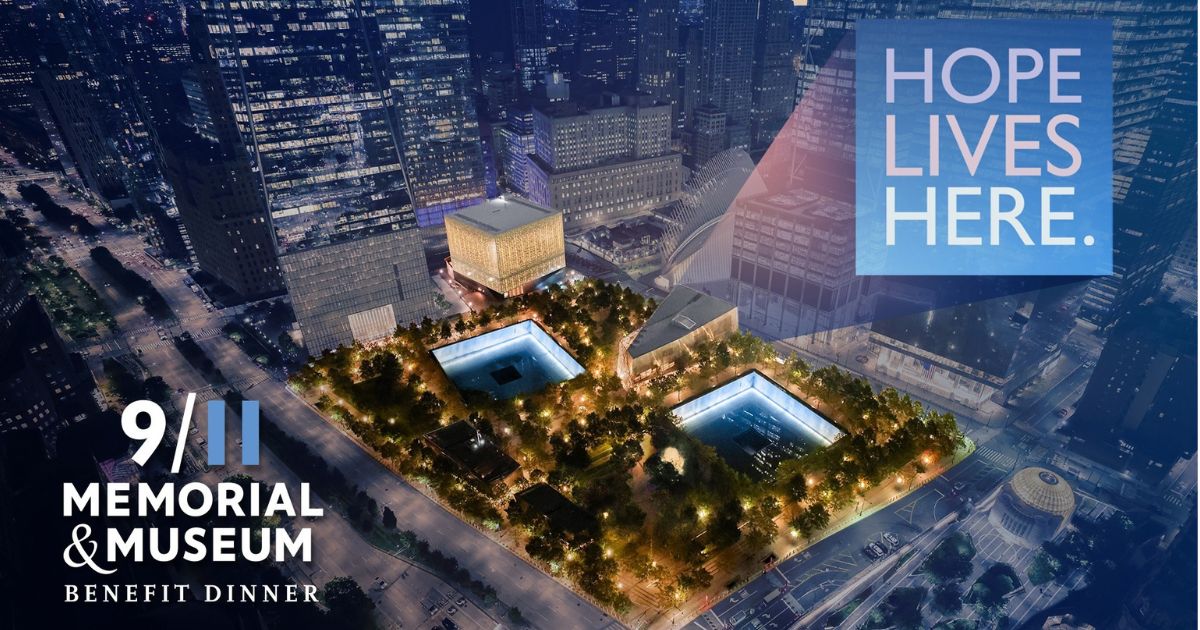 Aerial nighttime view of the 9/11 Memorial and Museum, with two illuminated reflecting pools at foreground 