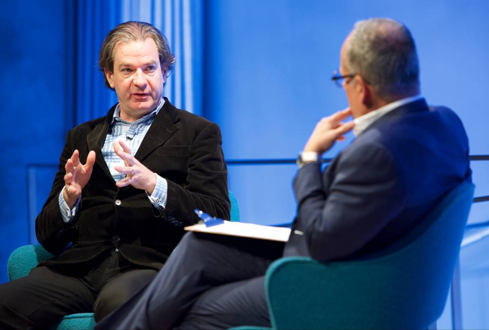 New York Times best-selling author and CNN National Security Analyst Peter Bergen gestures as he discusses his latest book with Clifford Chanin, the executive vice president and deputy director for museum programs. Chanin is slightly out of focus in the foreground as he listens with his hand to his face and his legs crossed.
