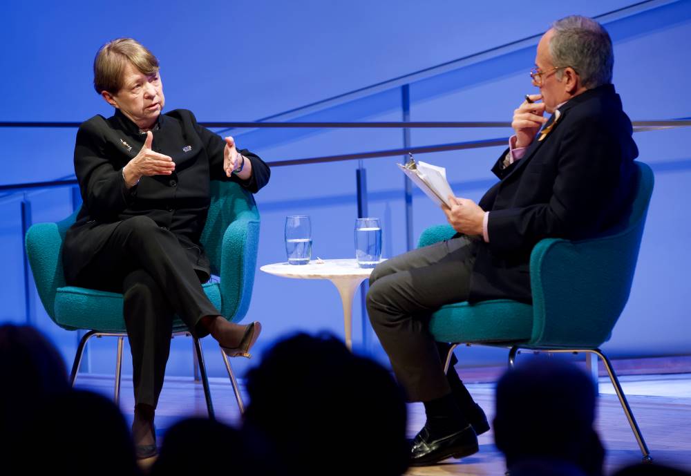 Former U.S. Attorney Mary Jo White of the Southern District of New York speaks with Clifford Chanin, the executive vice president and deputy director for museum programs, onstage at the Museum Auditorium. White gestures as she speaks to Chanin, who is holding a clipboard in one hand and a pen in the other.