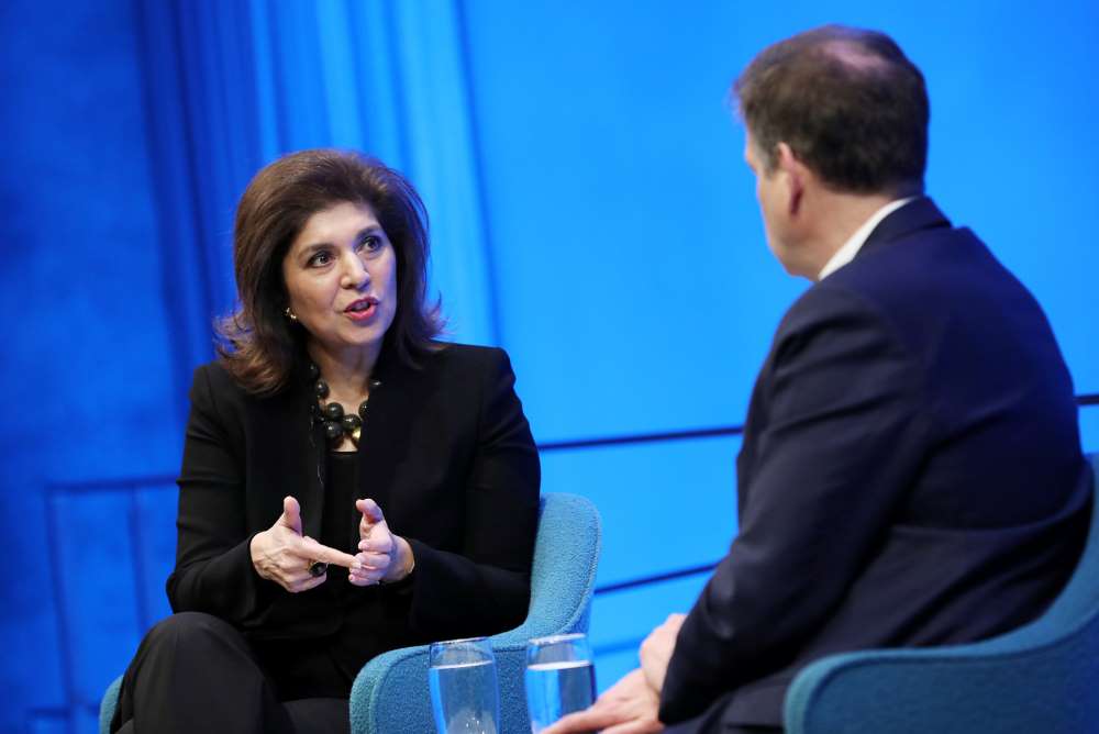 This close-up shot shows Author Farah Pandith gesturing with both hands as she speaks to Foreign Affairs editor Gideon Rose, who is in the foreground listening to her with his hands in his lap.
