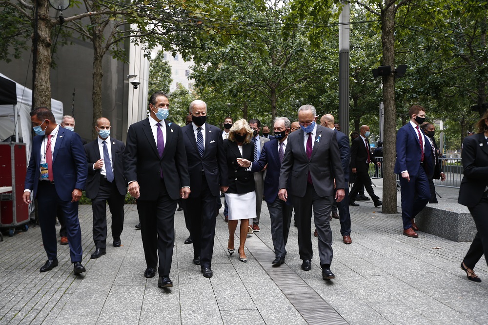 Elected officials wearing face masks walk toward the commemoration ceremony on the Memorial plaza.
