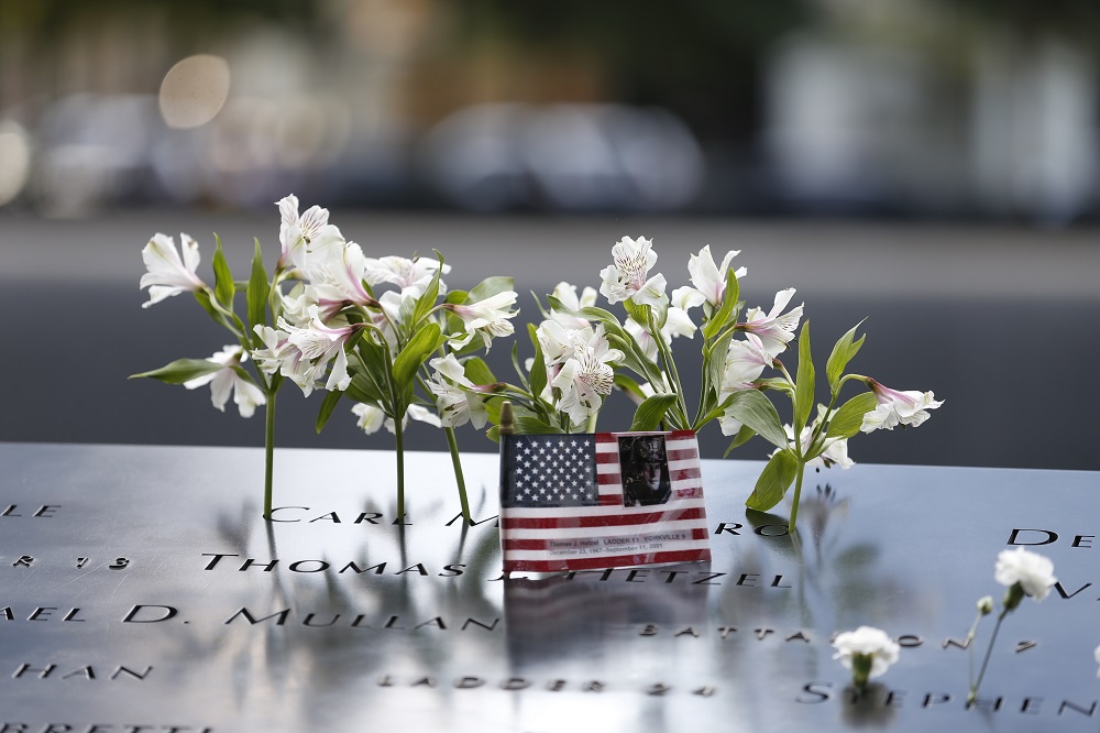 Flower tributes and an American flag are left on the Memorial.