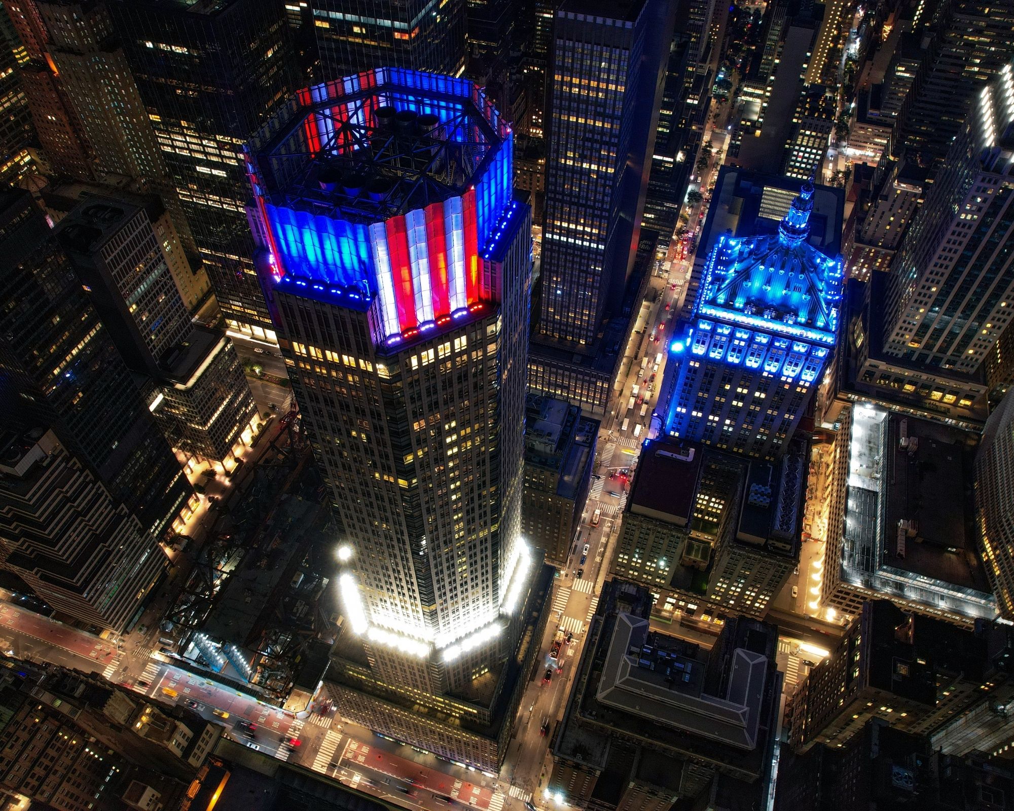 Manhattan buildings lit in red, white, and blue (left) and blue (right)