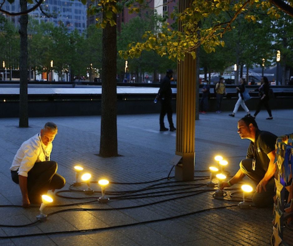 Two workers arrange lightbulbs and wires on the plaza