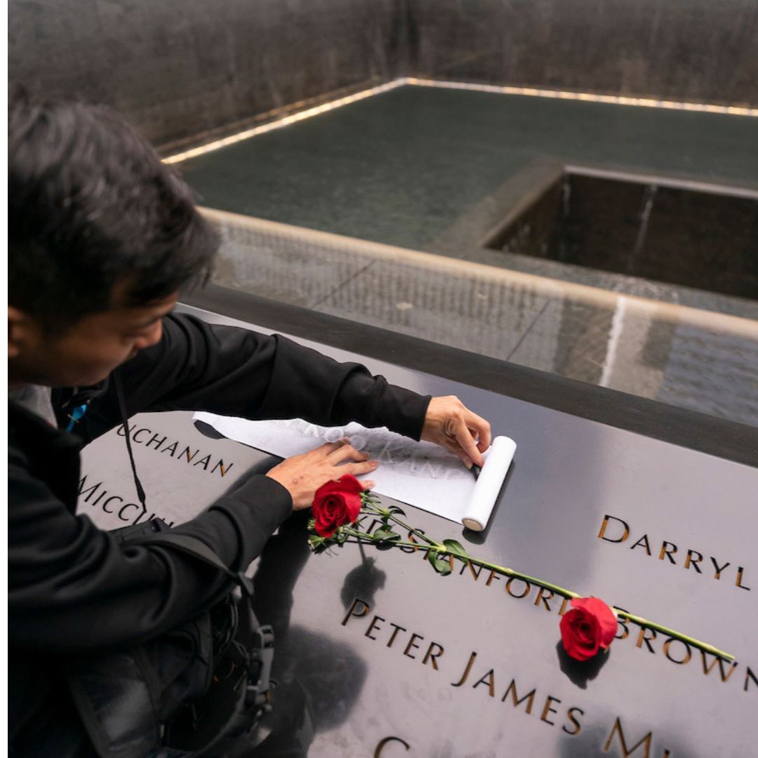 A young boy traces the makes an impression of a name on the Memorial