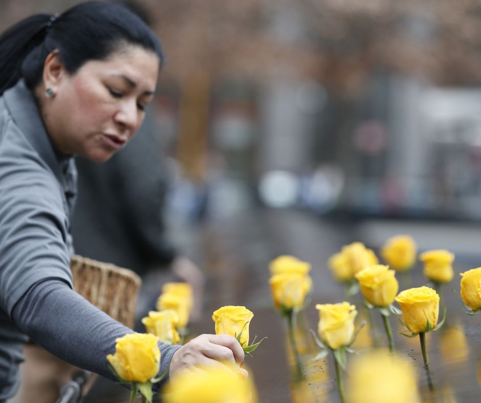 A volunteer places yellow roses on the Memorial to mark Veterans Day