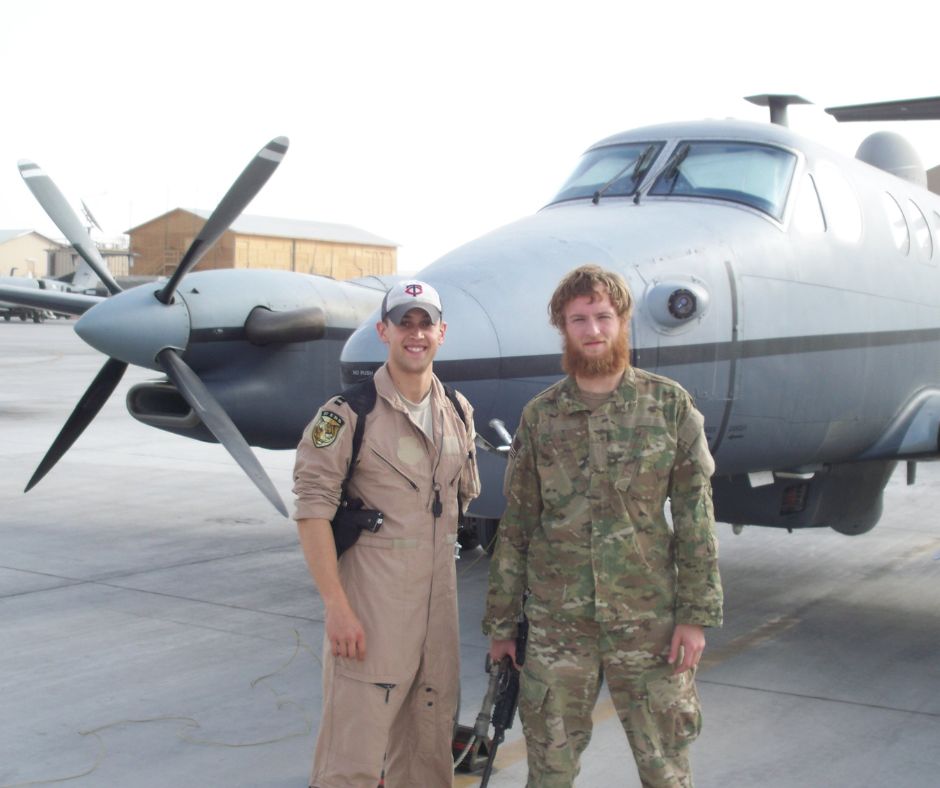 Phil Caruso (right) in uniform with fellow servicemember, in front of military plane