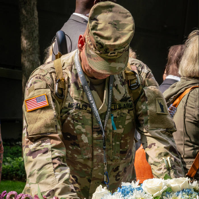 a US Army soldier in camoflage bows at a Memorial Glade monolith