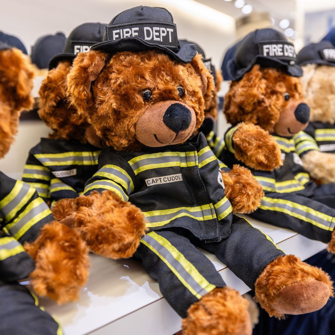 Teddy bears wearing FDNY uniforms on a shelf