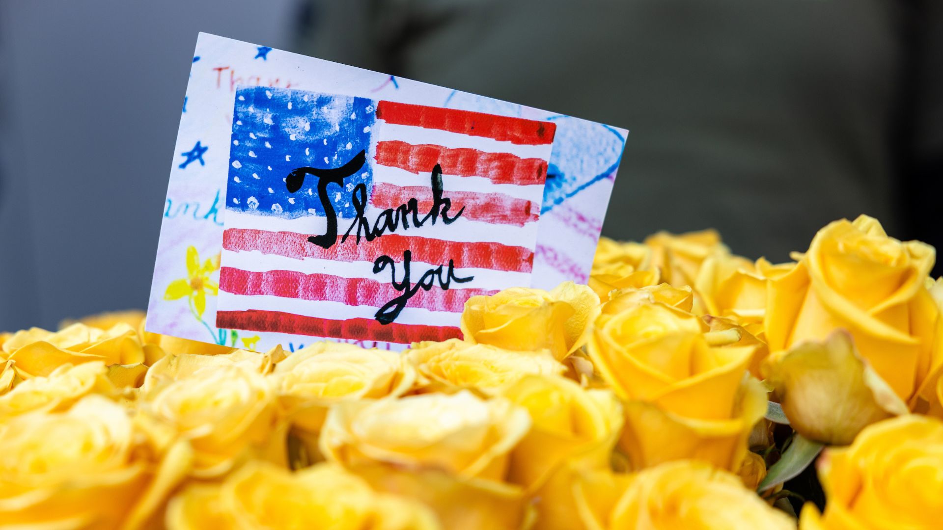 Close-up of yellow roses with an image that shows the American flag and the text THANK YOU