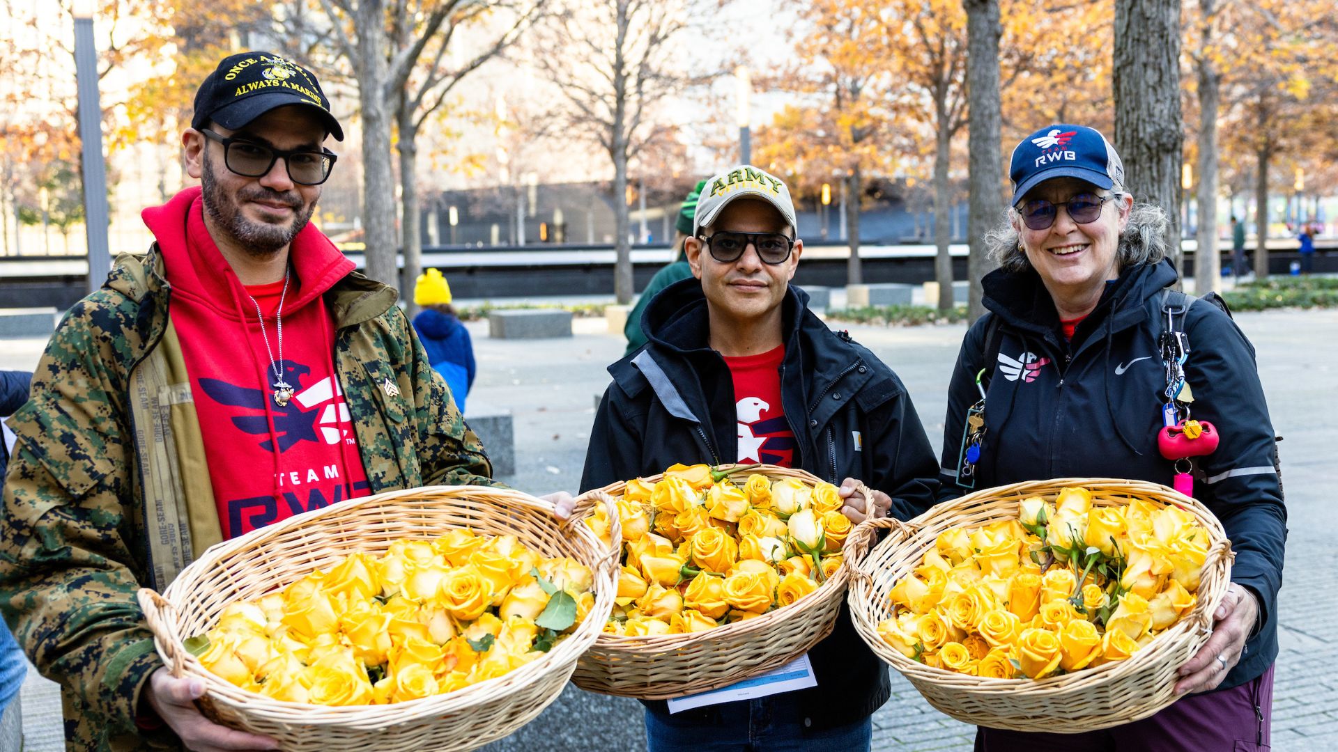 Three men hold baskets of yellow roses on the Memorial plaza