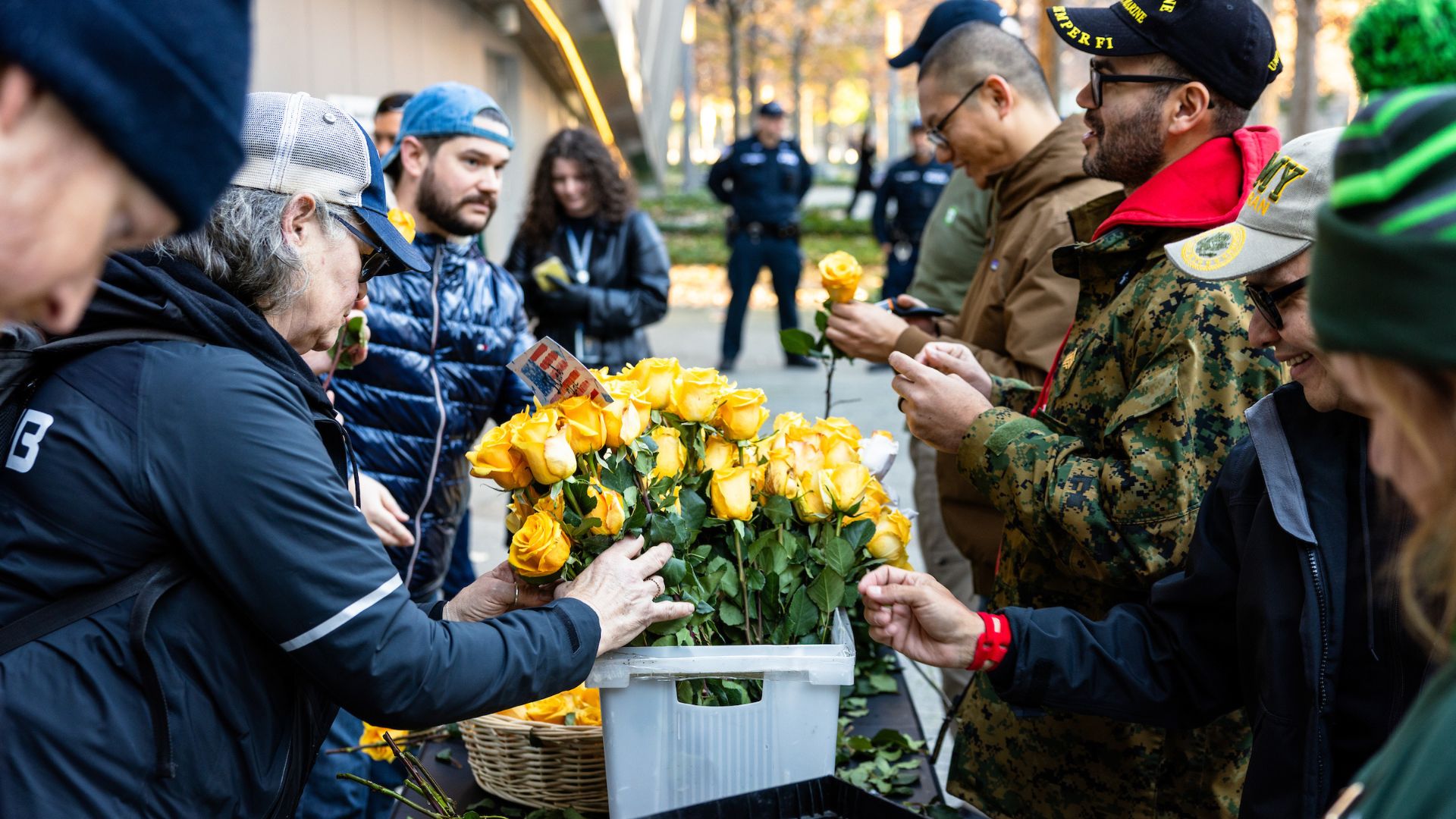 People hover over a bucket of yellow roses as they prepare to place the on the Memorial