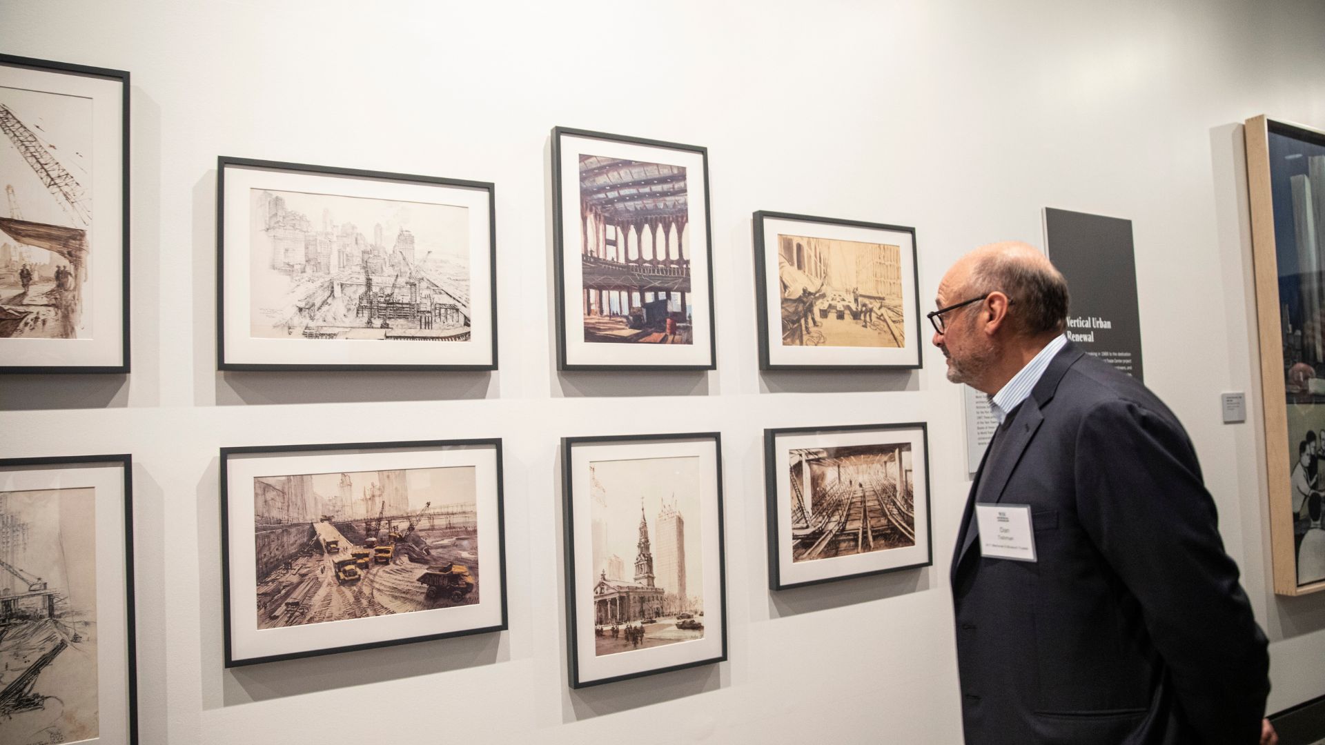 Side view of a man looking at a wall of images depicting different stages of the World Trade Center construction