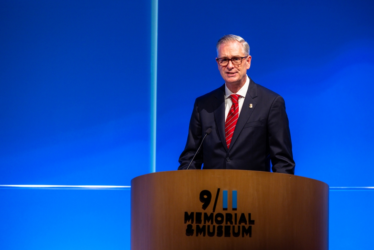 A man stands at a podium in front of a blue background