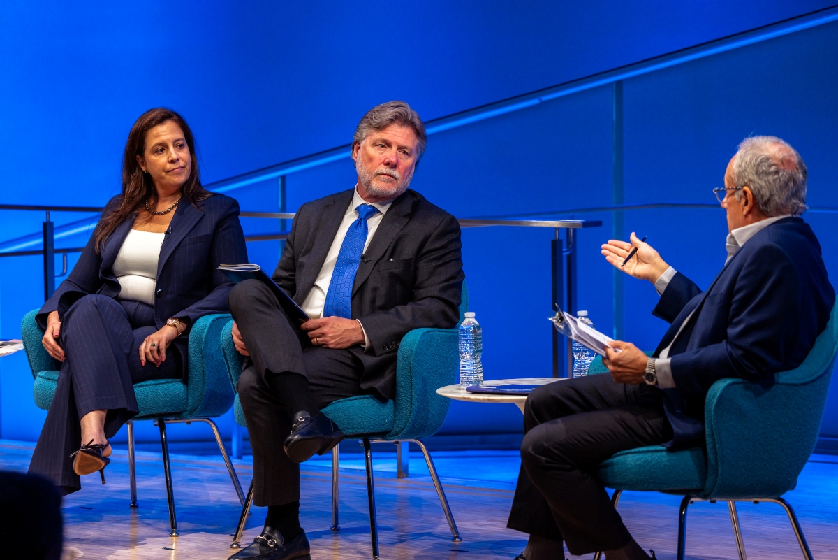 Three people are in view with blue behind them