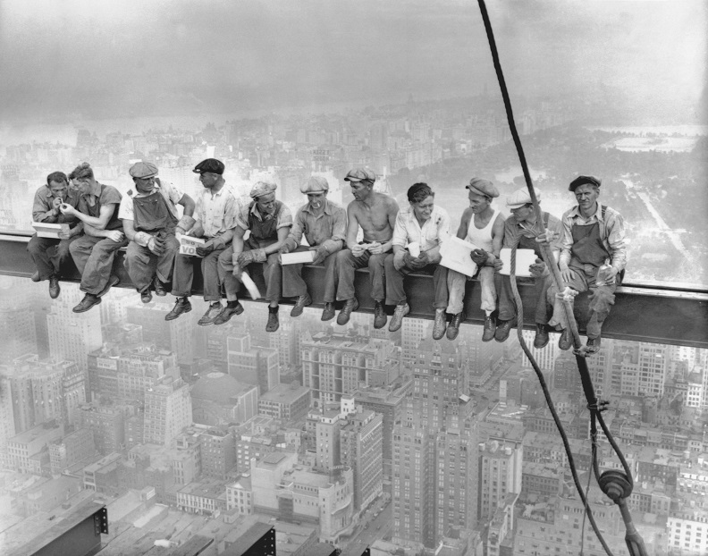 In this historical photograph from 1932, ironworkers eat lunch on a steel beam in Manhattan. 