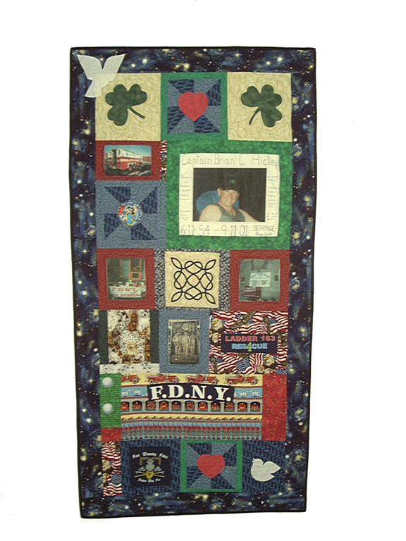 A quilt paying tribute to FDNY Captain Brian Hickey features a transfer photo of Hickey and various other ornamentation. The quilt also features embroidered shamrocks, hearts, and fire trucks. 