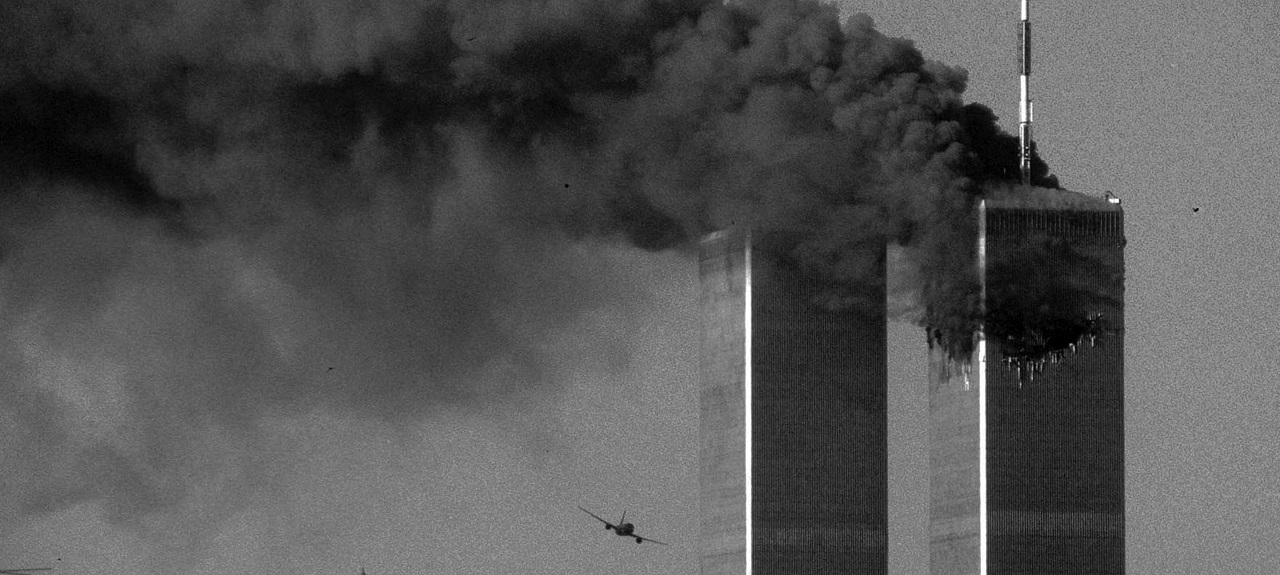 Smoke billowing out of the North Tower as a plane is flying towards the South Tower. 