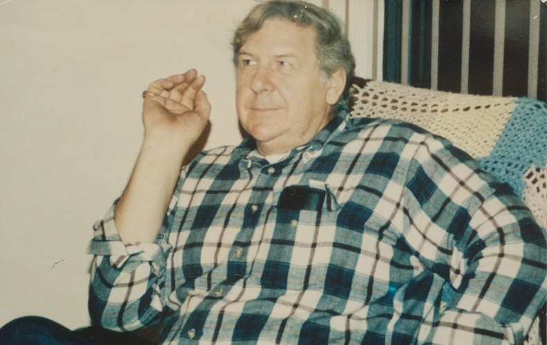 William Macko sits in a chair in a plaid shirt in this old photo. 