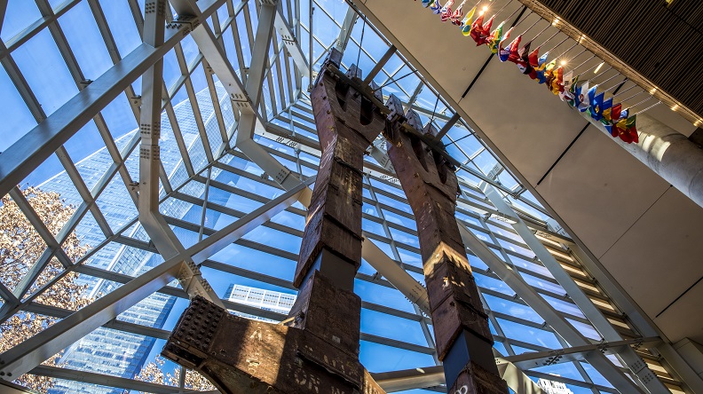 Two eighty-foot tall steel columns, known as the Tridents, tower over the interior of the museum Pavilion. One World Trade Center points skyward outside the windows. 