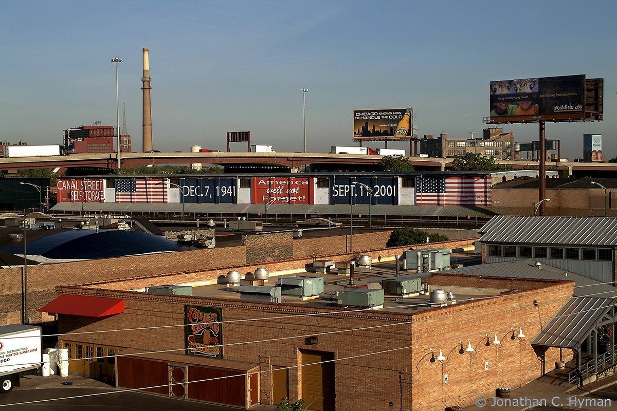 Five-paneled mural along a highway overpass: two American flags; the date of the Pearl Harbor attack; the date of the September 11 attacks; and the words "America will not forget." 