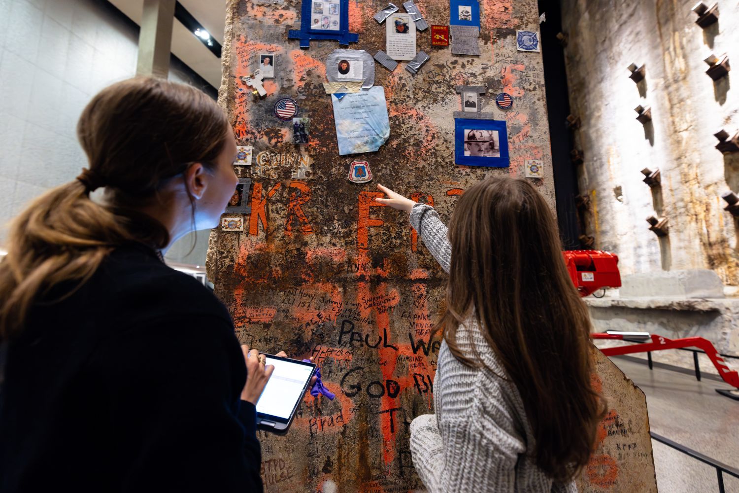 A woman using the guide on her phone stands with a child as they view the restored metal column