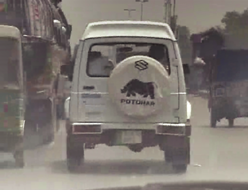 Still from video of the back of a white van with animal logo on the back on the road.