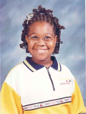 Asia Cottom, wearing a yellow polo shirt, smiles broadly for a yearbook photo.