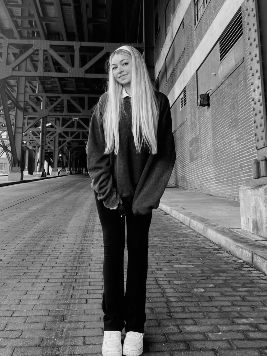 A young woman with long blonde hair stands on a brick walkway at Ohio State University.