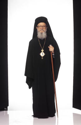 Greek Orthodox priest wearing all black vestments and holding a crosier.