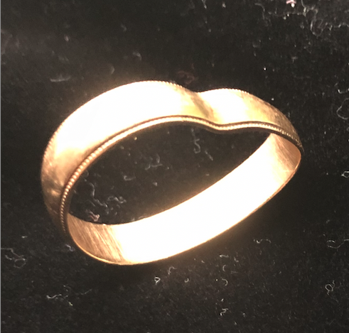 A gold wedding band with visible dent
