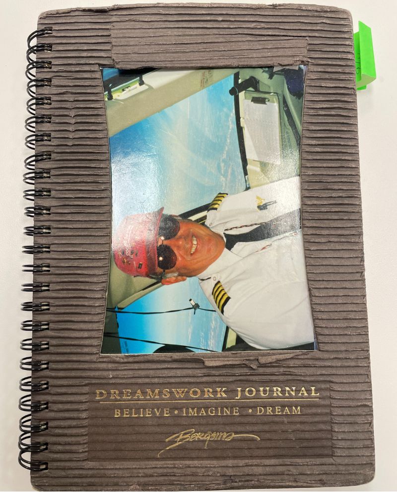 A brown spiral-bound journal with a photograph of David Friel embedded in cover