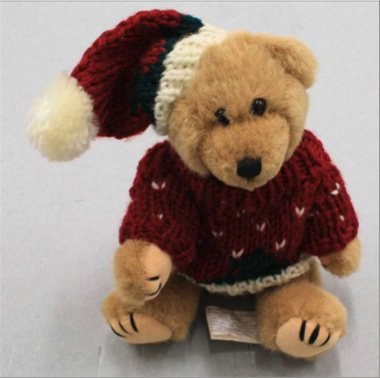 A light brown teddy bear wearing a maroon holiday sweater and matching Santa hat sits on a gray background