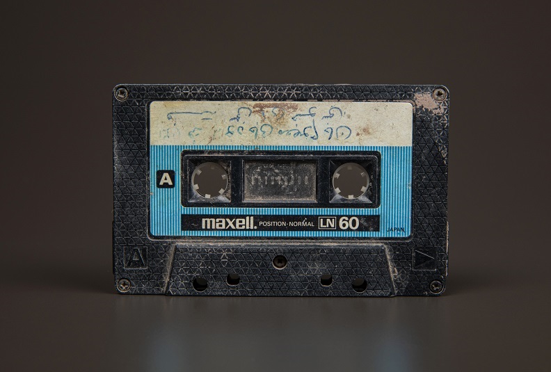 Maxell cassette tape with signs of wear, with Arabic writing on the blue and white label.