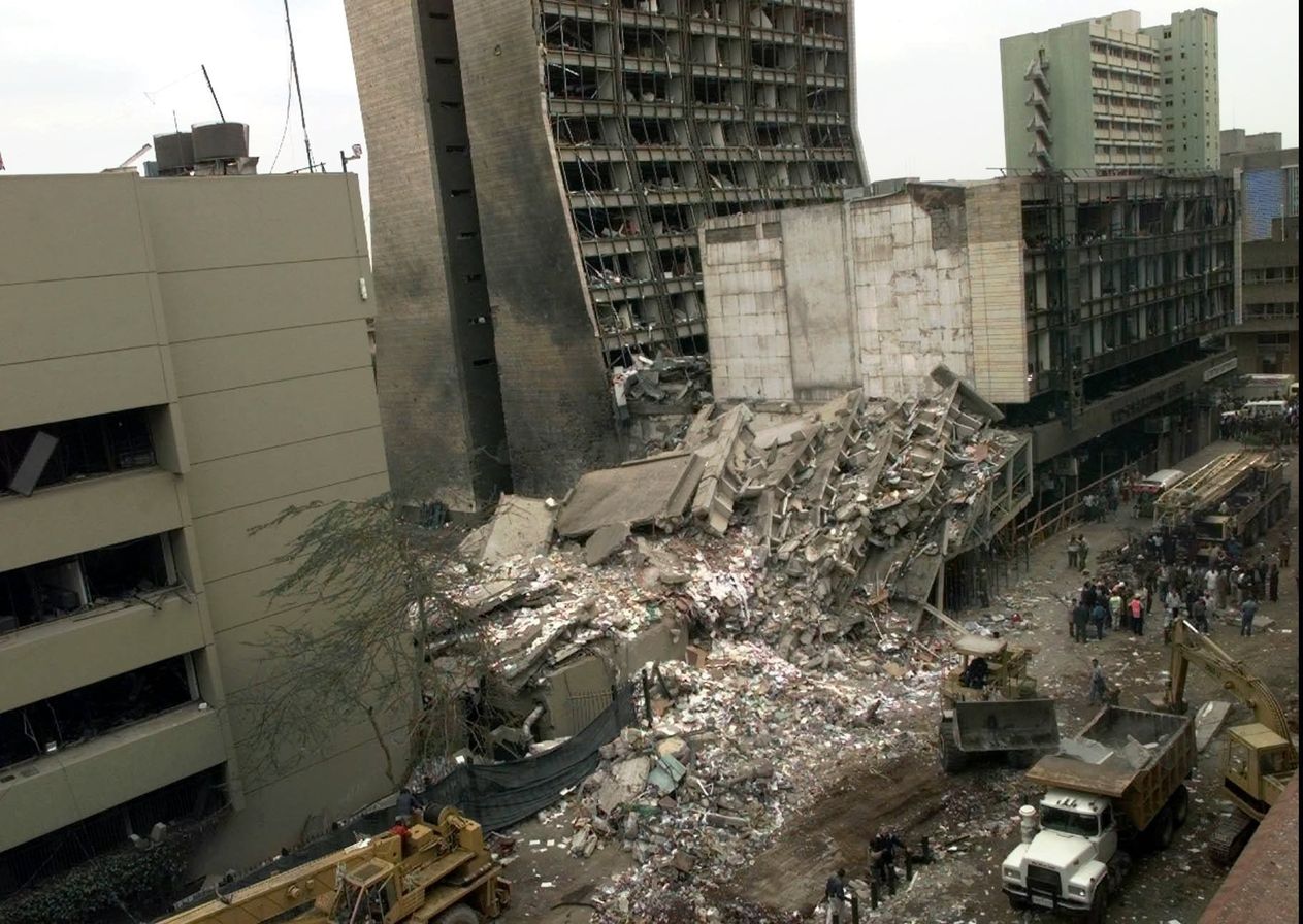 An aerial view of a destroyed building between partially damaged buildings.