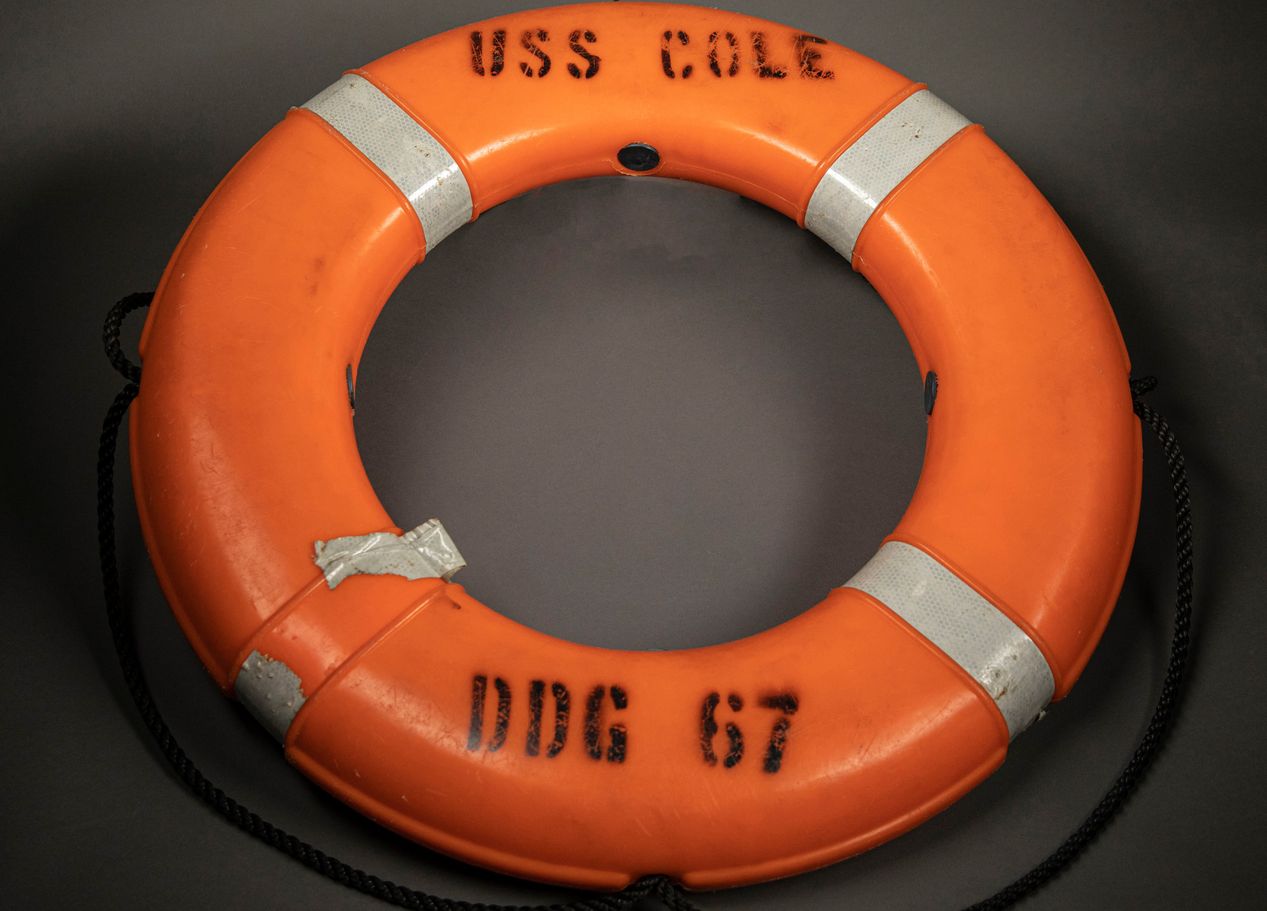 Orange life ring with the words "USS COLE" and "DDG 67" stamped on it.