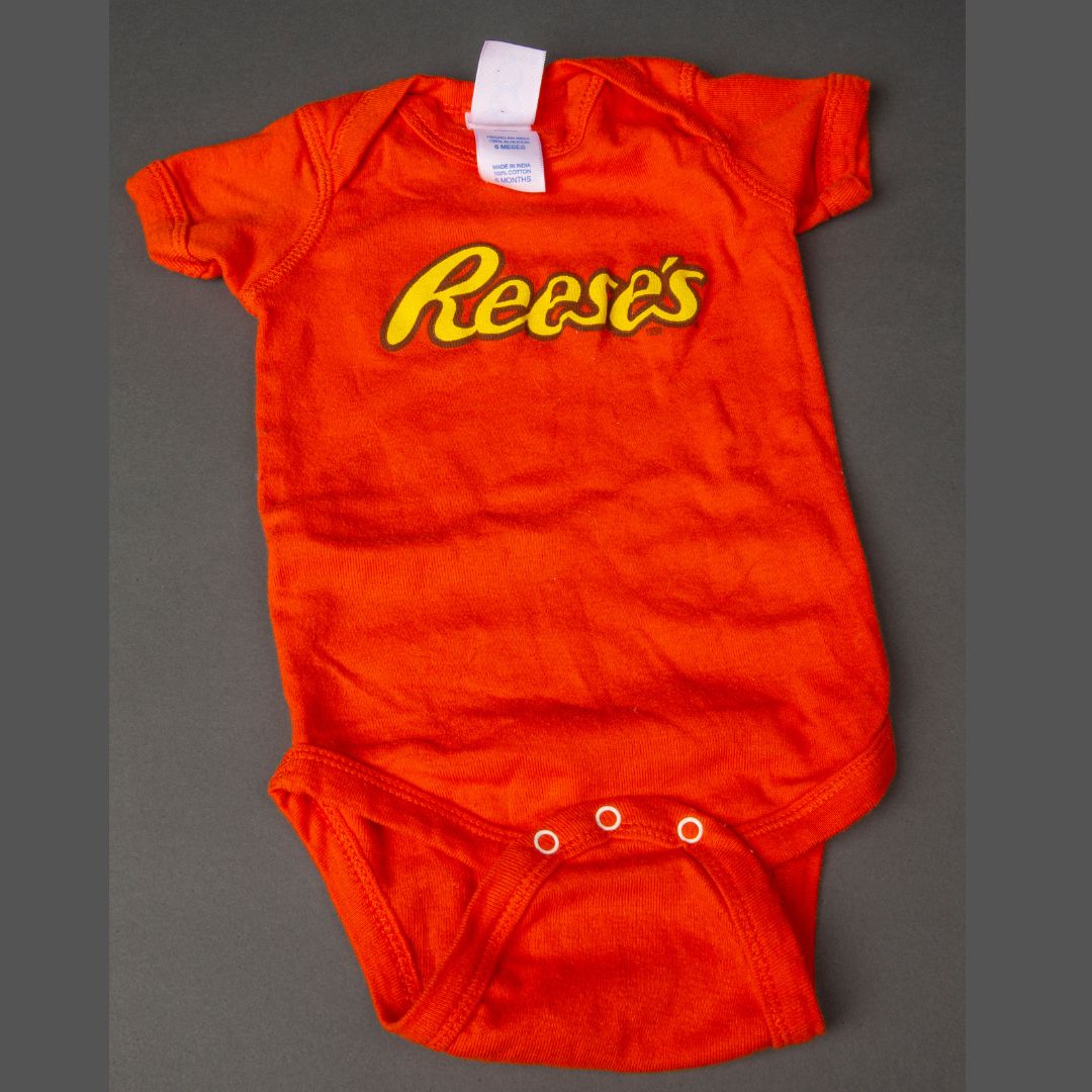 Child's orange onesie with Reese's logo