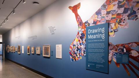 A blue exhibition wall shows a row of artwork, with a colorful rendering of a phoenix at the foreground.