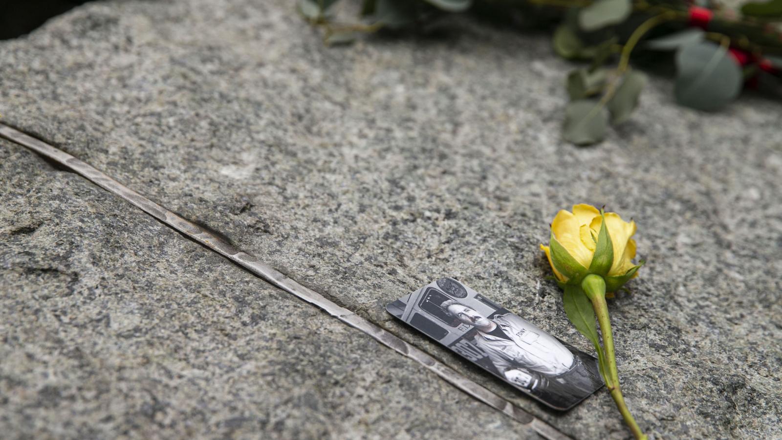 A photo of a man in front of an FDNY fire truck has been placed on a stone monolith at the Memorial Glade, which honors sick and fallen rescue and recovery workers. A yellow rose has been placed to the right of the photograph.
