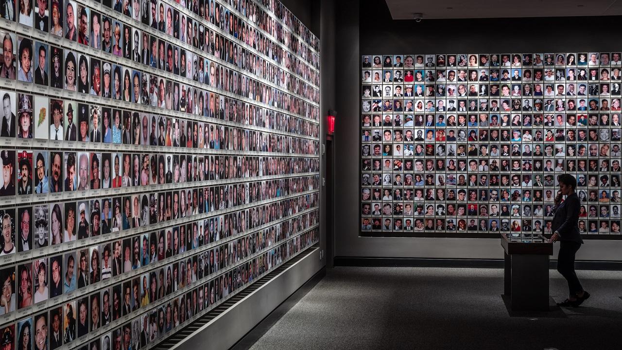 A woman visits the In Memoriam exhibition. On the wall in front of her and to her right are 2,983 portrait photographs of the victims.
