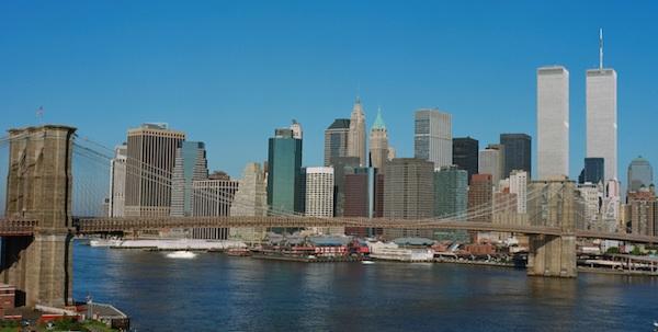 Skyline of lower Manhattan as seen from Brooklyn. Bright blue sky, the Brooklyn Bridge, and the Twin Towers are visible.