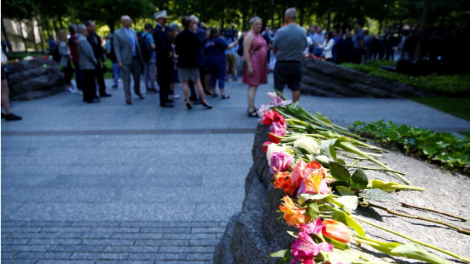 Colored roses on the Memorial Glade, with a crowd visible in the background