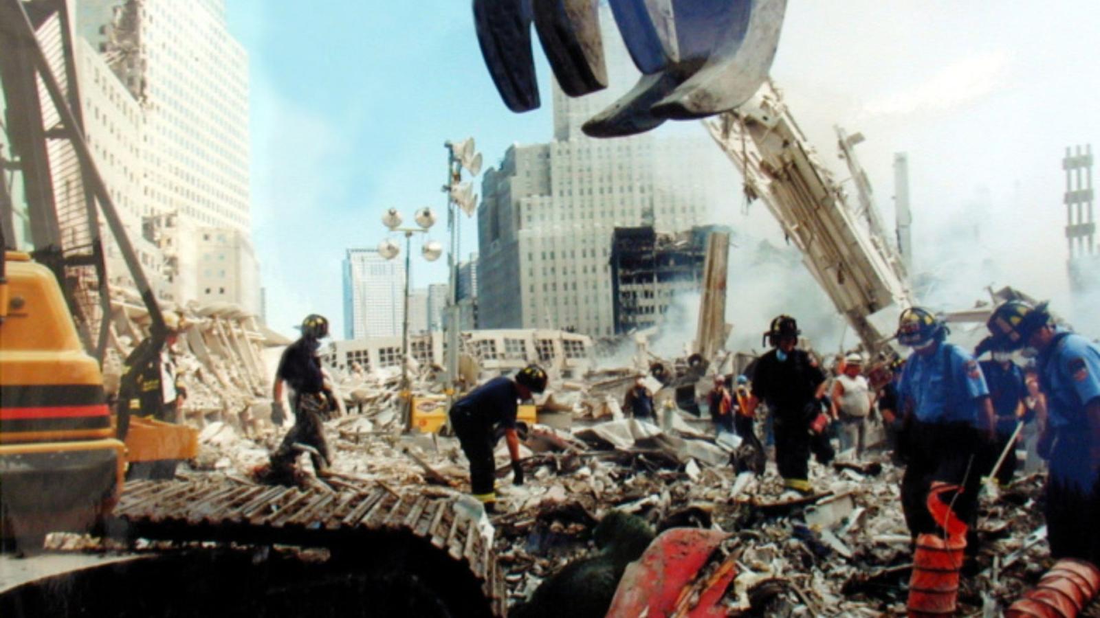 Uniformed rescue and recovery workers and a crane among building ruins